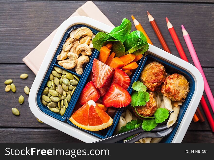Healthy food lunch box. Vegan food: beans meatballs, pasta, vegetables, berries, seeds and nuts in a container