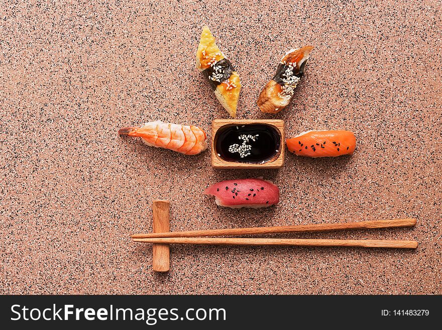 Assorted sushi set on a brown stone background. Japanese food sushi, soy sauce, chopsticks. Top view, copy space.