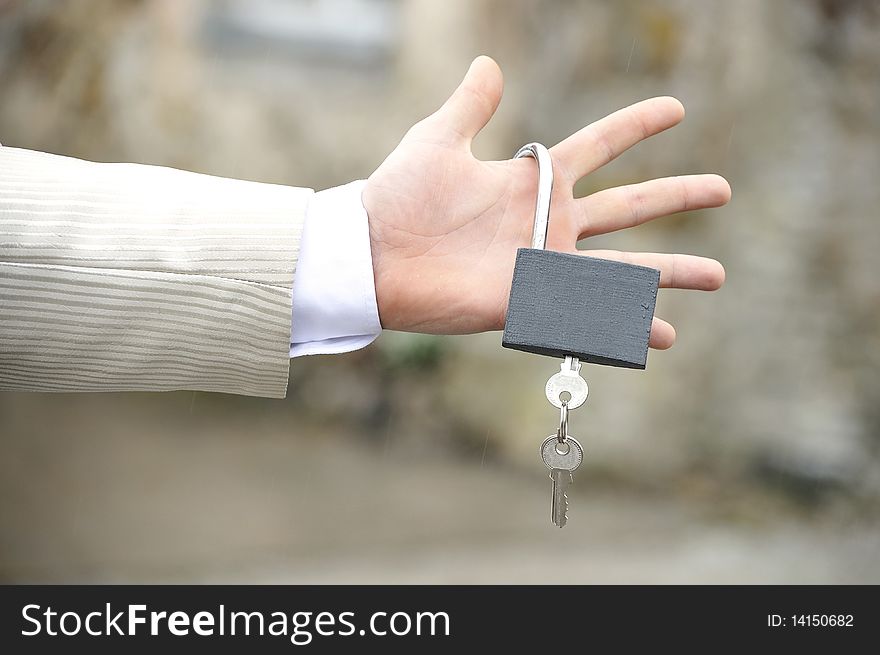 Man's hand holding gray lock with key