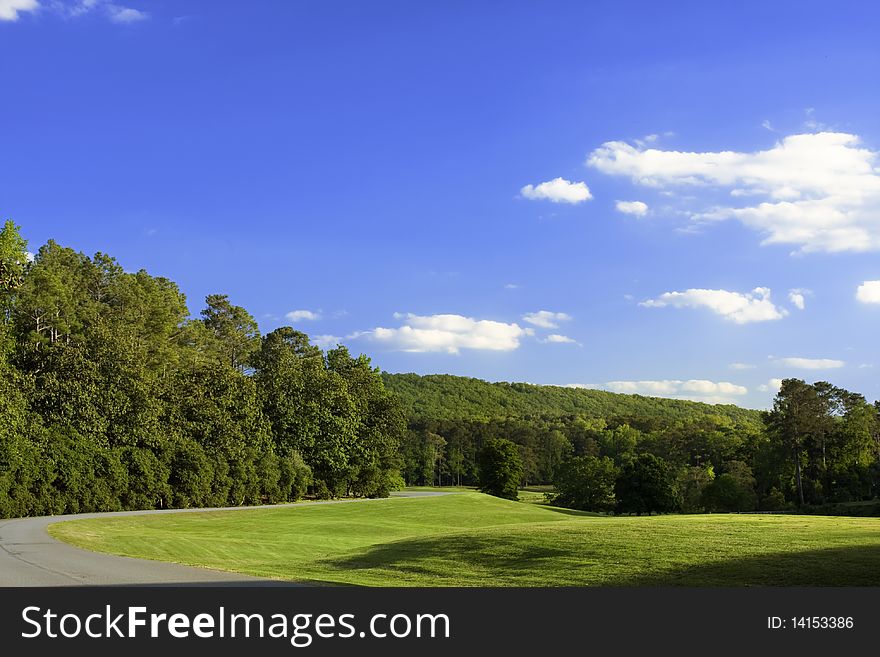 Blue sky, curved road, green grass and trees. Blue sky, curved road, green grass and trees