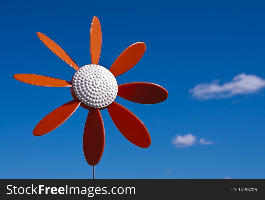 A vintage plastic flower windmill on a blue sky.