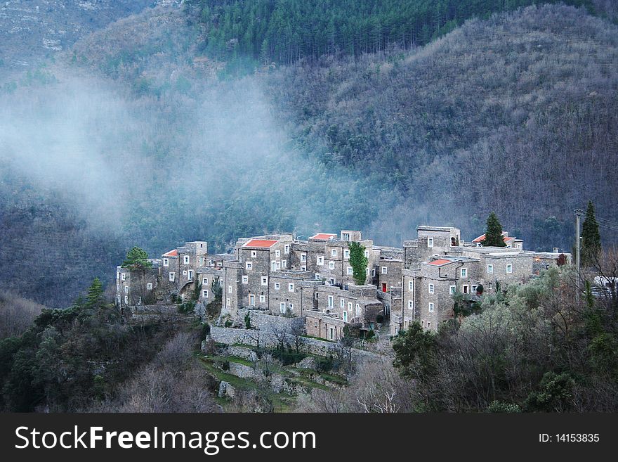 Small village on the hill, with a low cloud on it, italian country