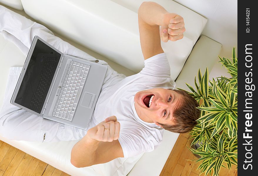 Top view of a happy youngman sitting on couch and using laptop. Top view of a happy youngman sitting on couch and using laptop
