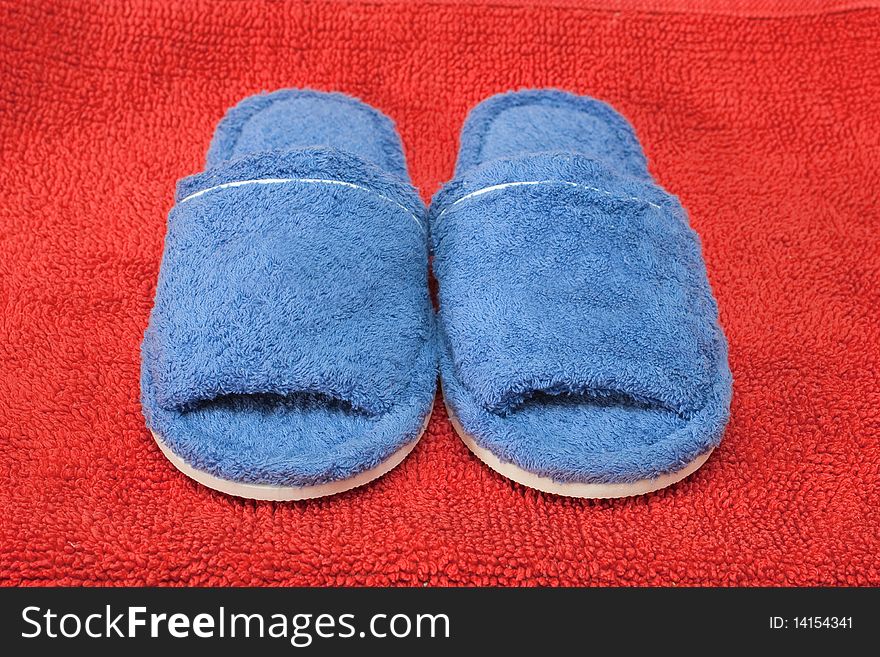 Blue terrycloth slippers on a red background. Blue terrycloth slippers on a red background.