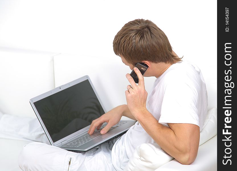 Portrait of a  young man speaking on mobile phone with a laptop