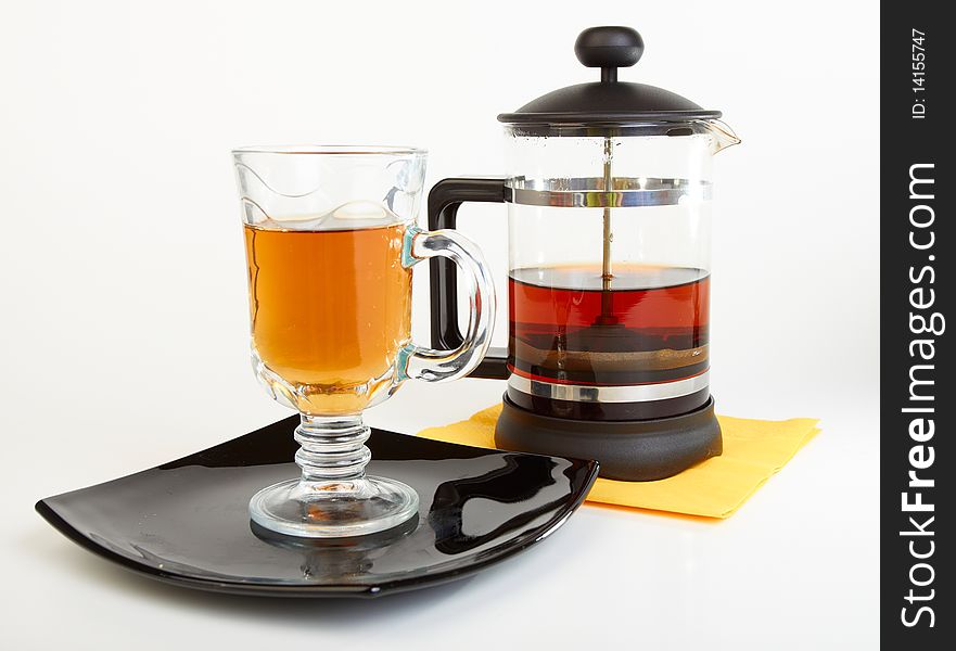 Сup of tea on black plate with teapot on white background