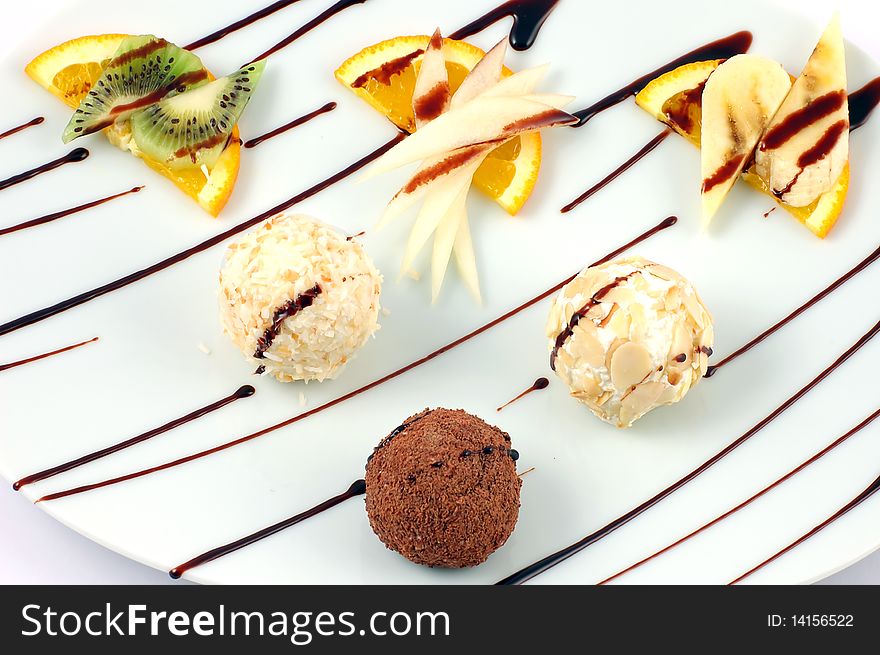 Fresh dessert from fruit and chocolate spheres on a white dish