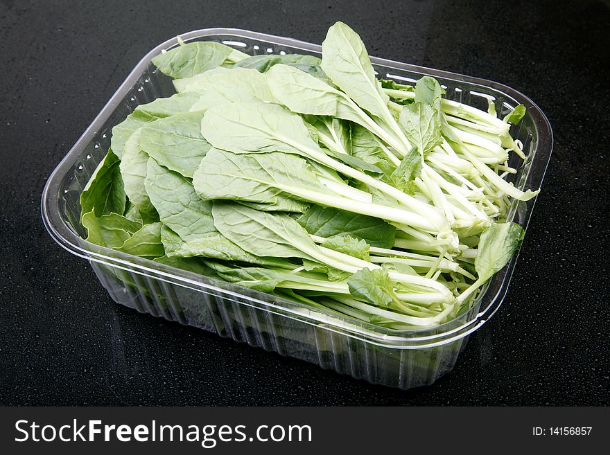 Fresh green pollution-free vegetables in a glass box.(on dark background ). Fresh green pollution-free vegetables in a glass box.(on dark background )