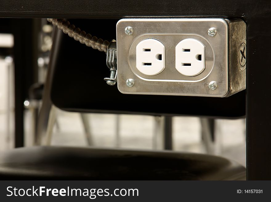 Close-up of an electrical outlet underneath student tabletop in school laboratory. Close-up of an electrical outlet underneath student tabletop in school laboratory.