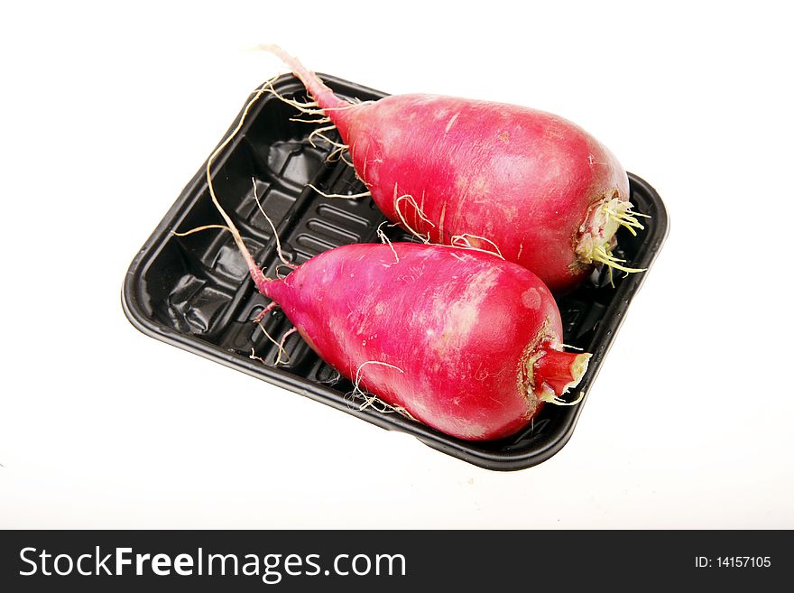 Two fresh red radish in a dark plastic box.(on white)