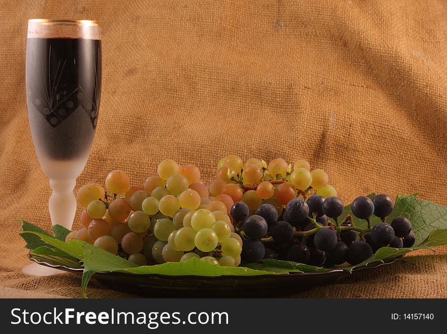 Glass of wine, grapes on a plate on the old background