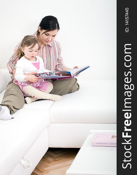 Mother and daughter reading book at sofa