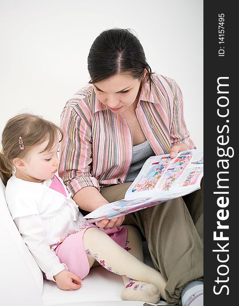Mother and daughter reading book at sofa