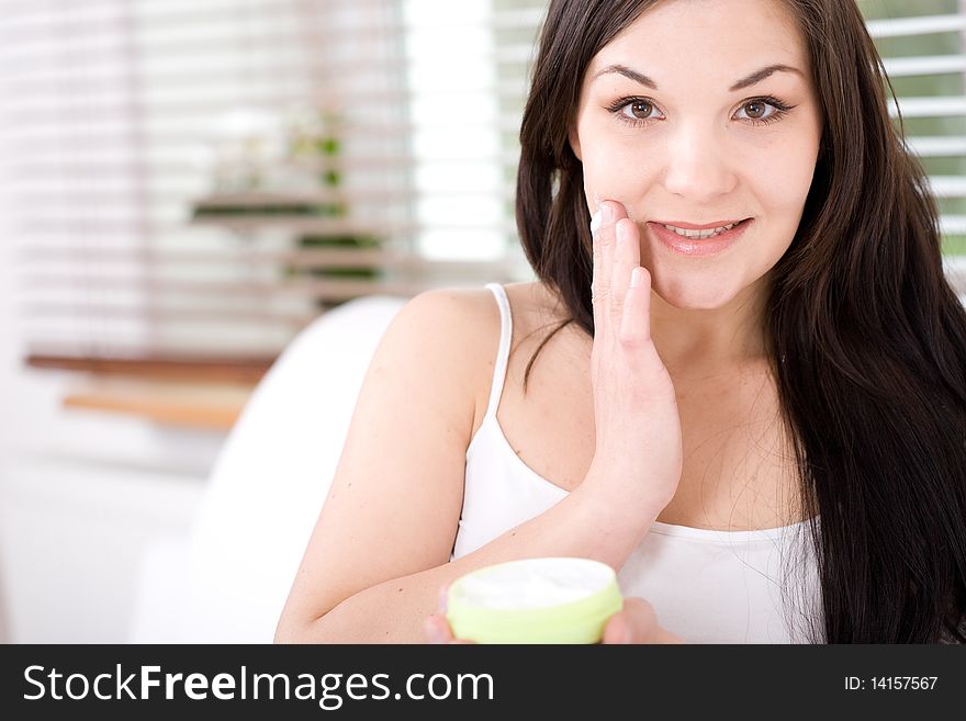 Young happy woman applying cream