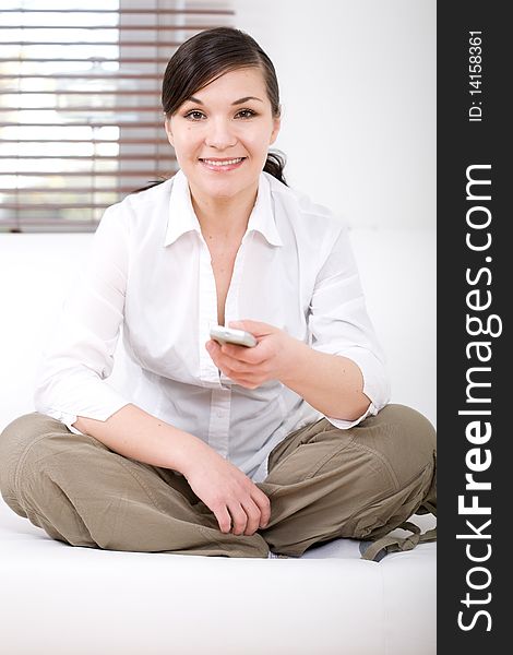 Young happy woman sitting on sofa with remote control. Young happy woman sitting on sofa with remote control