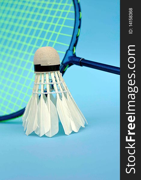 The main focus of the picture is the shuttercock and the racket just as additional subject with a blue background. The main focus of the picture is the shuttercock and the racket just as additional subject with a blue background