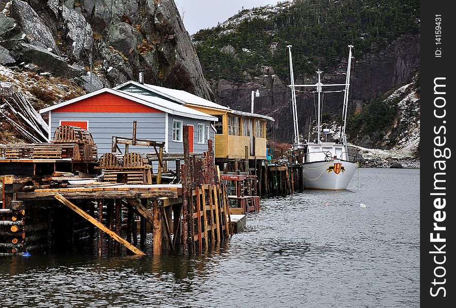 Fishing wharf or pier with buildings and a boat docked alongside at the end of a fjord. Fishing wharf or pier with buildings and a boat docked alongside at the end of a fjord.