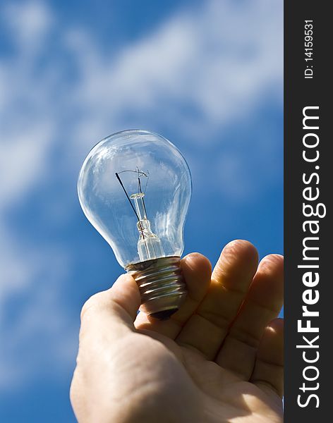 Man holding bulb against blue sky