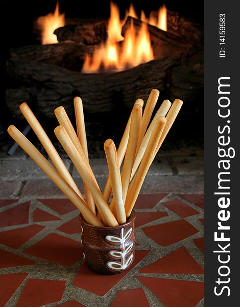 Bread sticks in a dish with a fire in the background.  Low light image. Bread sticks in a dish with a fire in the background.  Low light image.