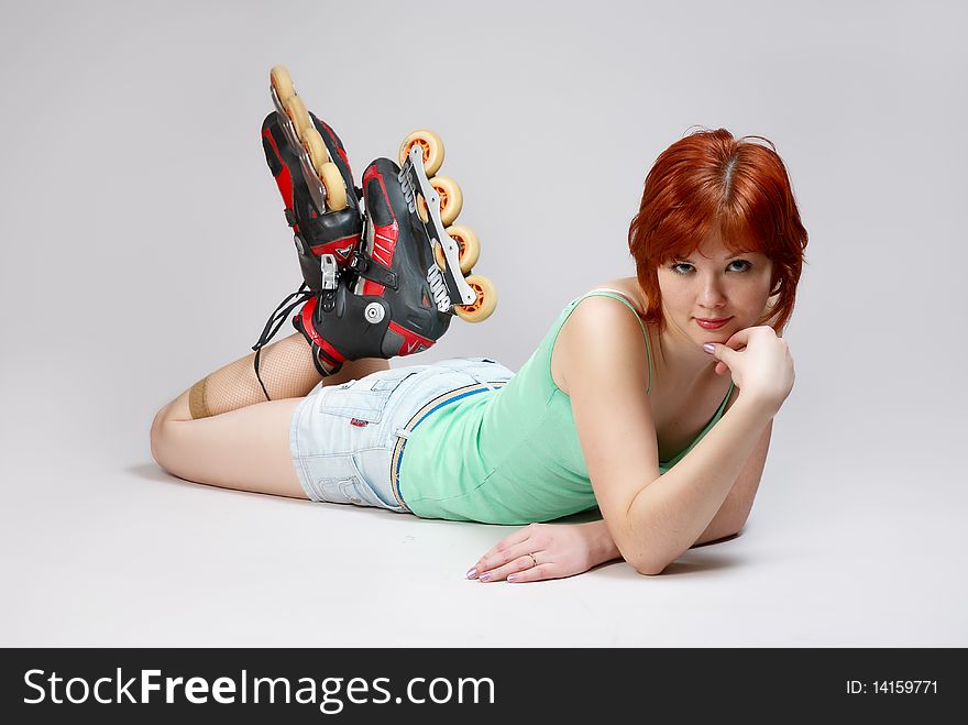 Smiling beautiful young woman on roller-skates lying on the floor , on white background. Studio shot