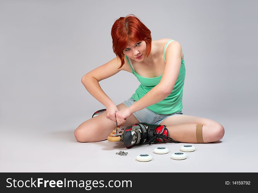 Young woman sitting on the floor and repair roller-skates. Studio shot on white background. Young woman sitting on the floor and repair roller-skates. Studio shot on white background.