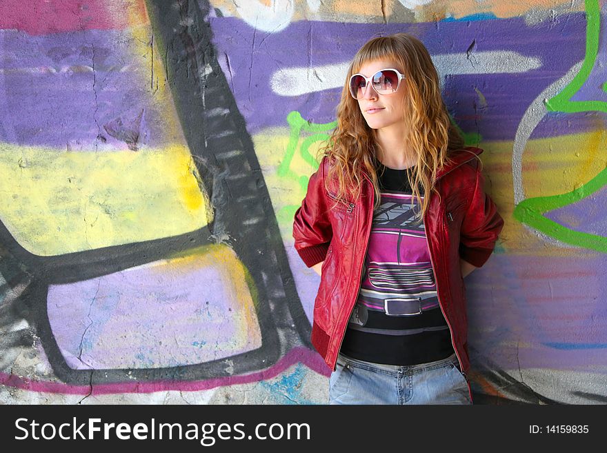 Young girl stands in front of a graffiti wall. Young girl stands in front of a graffiti wall