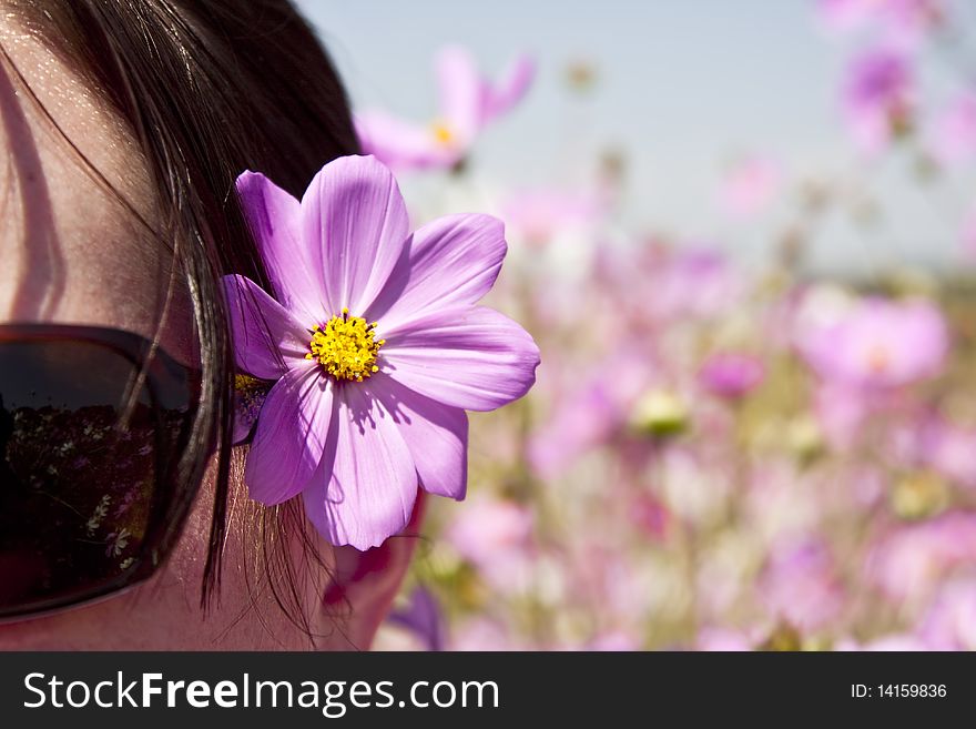 Close-up natural looking photograph of a young lady wearing sunglasses and a pink flower in her hair. Close-up natural looking photograph of a young lady wearing sunglasses and a pink flower in her hair.