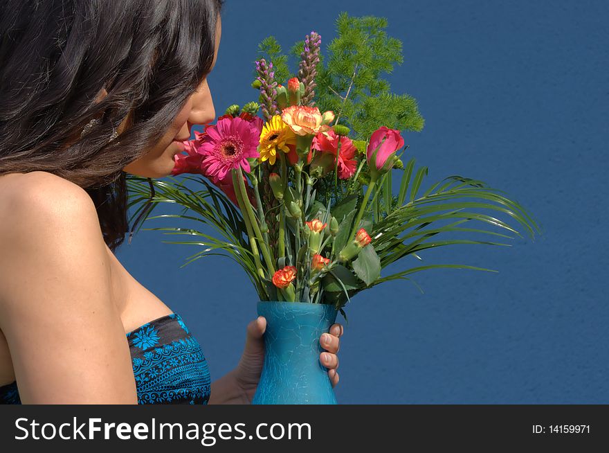 Woman smelling a bouquet of flowers in a vase. Woman smelling a bouquet of flowers in a vase