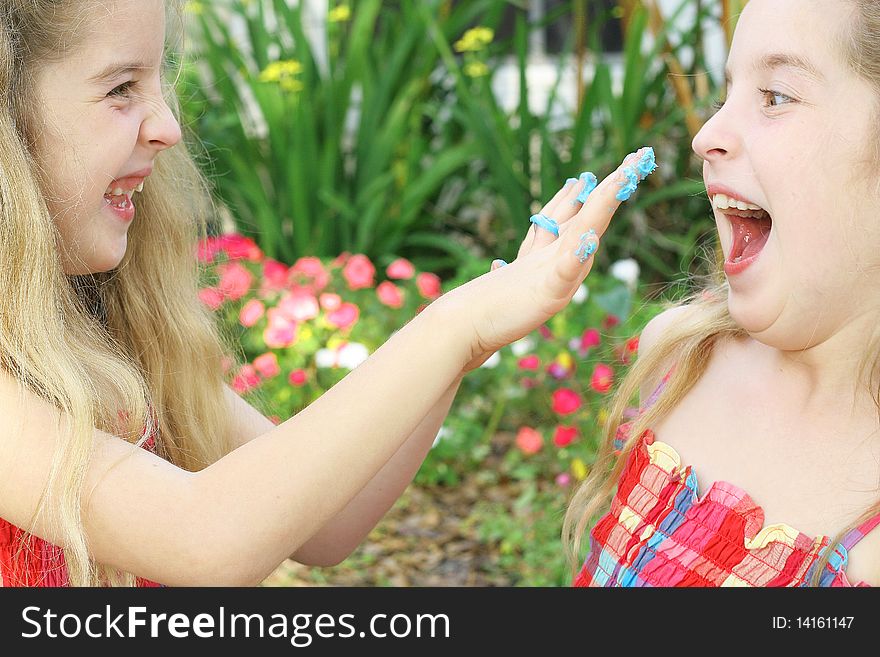 Little Girl Putting Frosting On Sister