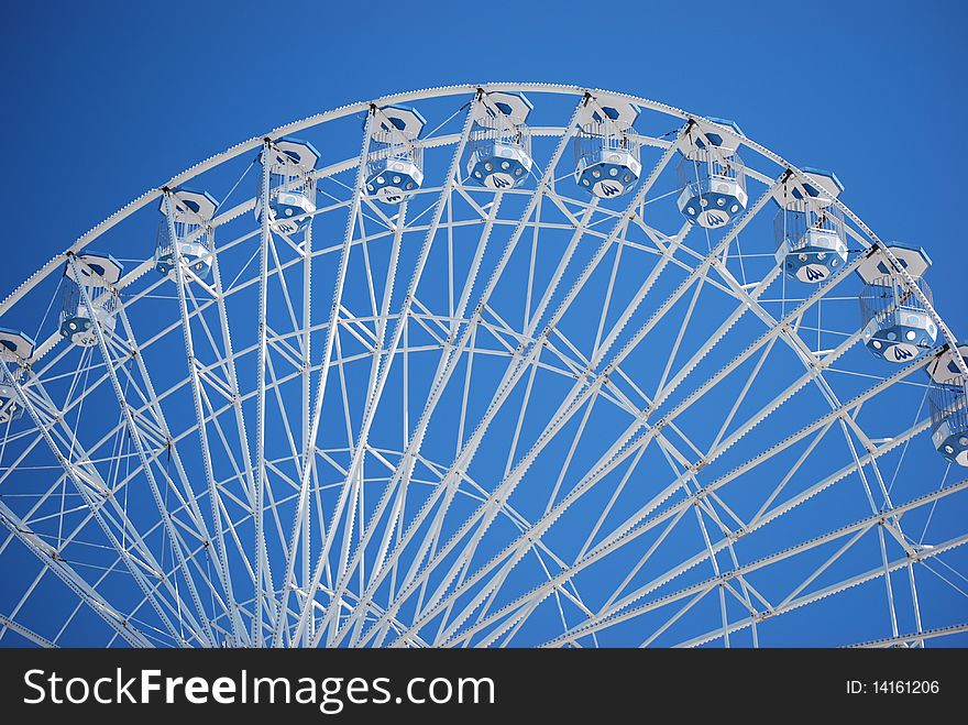 A semicircle of a ferris wheel ride up in the blue sky. A semicircle of a ferris wheel ride up in the blue sky.