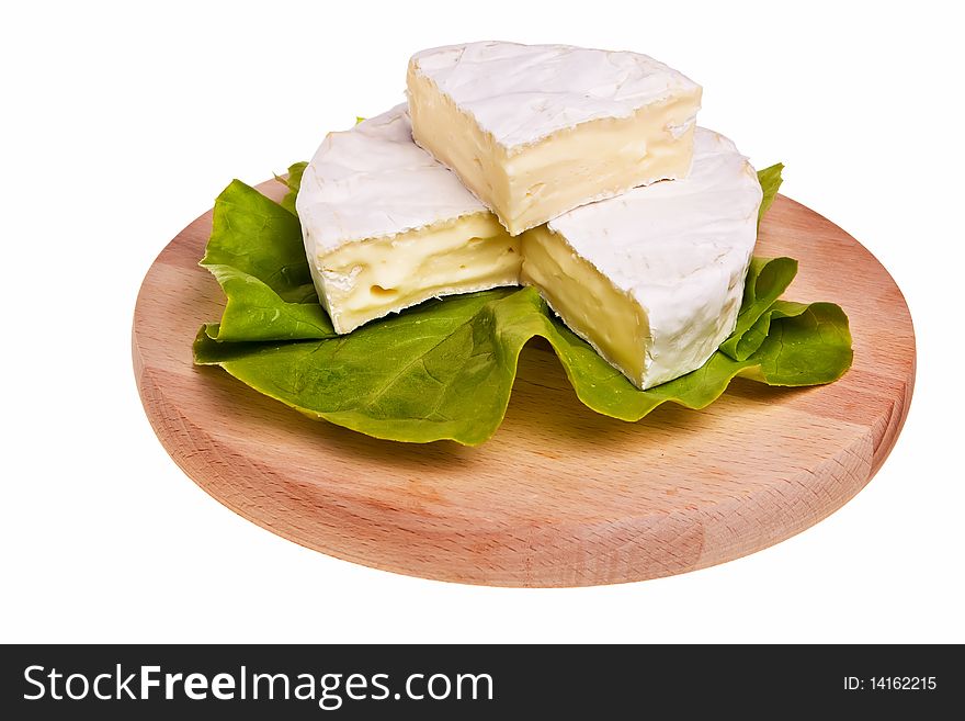 Round camembert cheese on lettuce on cutting board. Round camembert cheese on lettuce on cutting board.