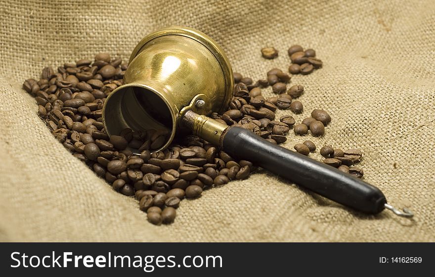 Coffee pot with roasted coffee beans, on linen background