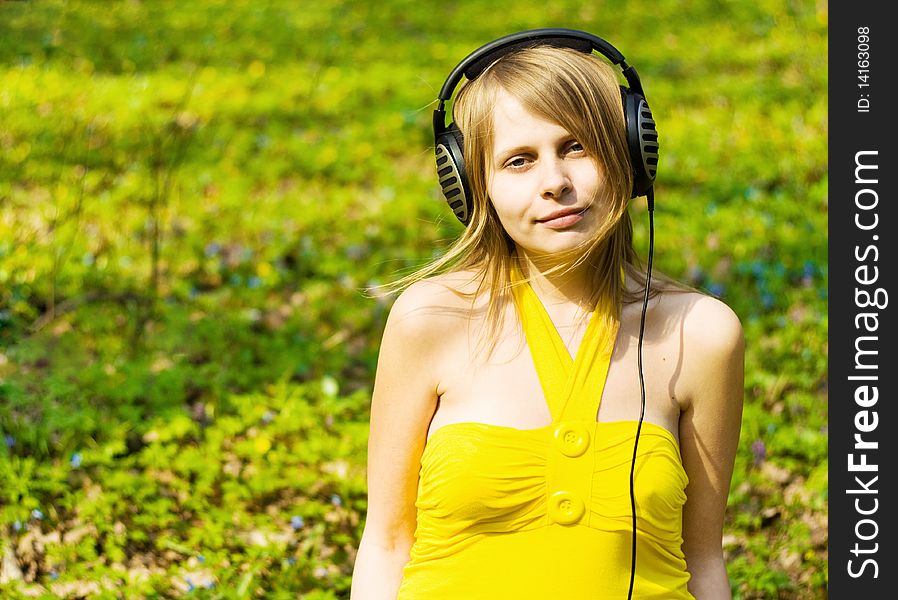 Blond girl listening music in headphones. Outdoor shot