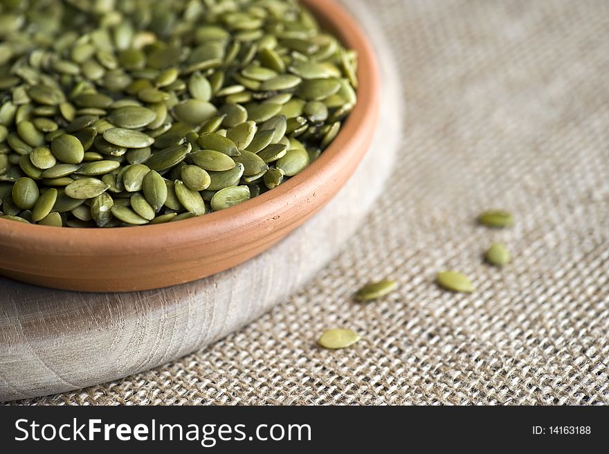 A Dish Of Pumpkin Seeds On A Wooden Board Against A Hessian Cloth. A Dish Of Pumpkin Seeds On A Wooden Board Against A Hessian Cloth