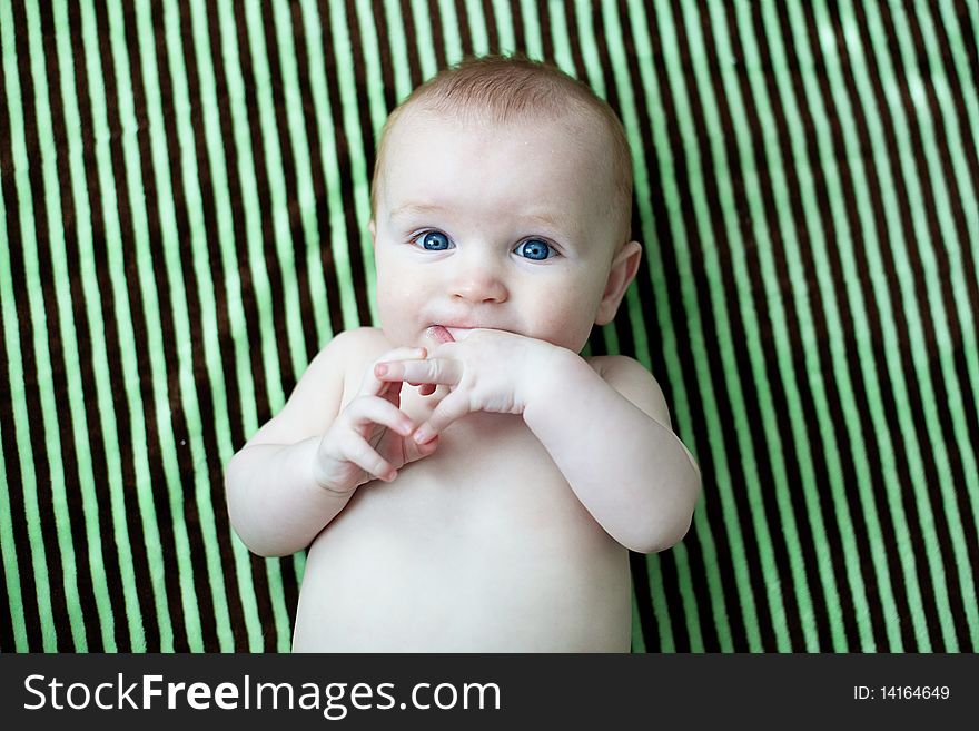 Baby laying on a striped blanket sucking on his fingers. Baby laying on a striped blanket sucking on his fingers.