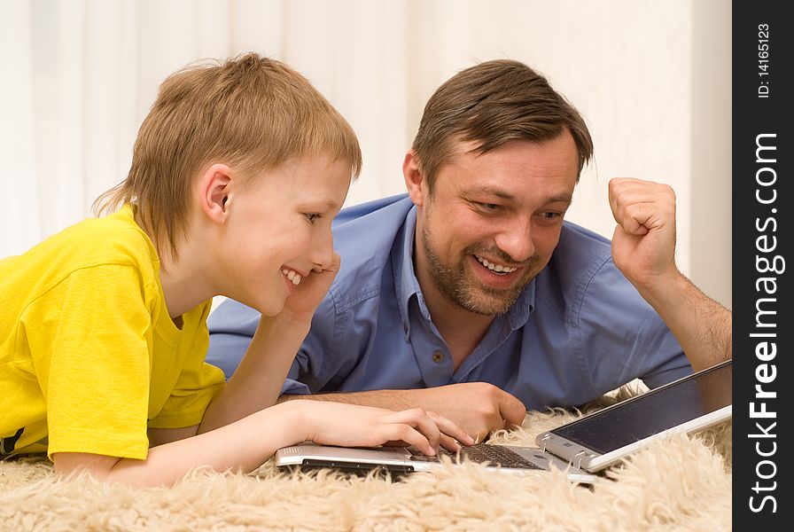 Father and son is on the carpet with laptop. Father and son is on the carpet with laptop