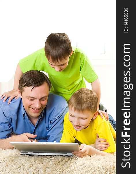 Father with his sons is on the carpet with laptop