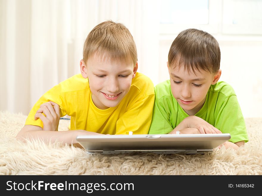 Two little brothers lie  with laptop