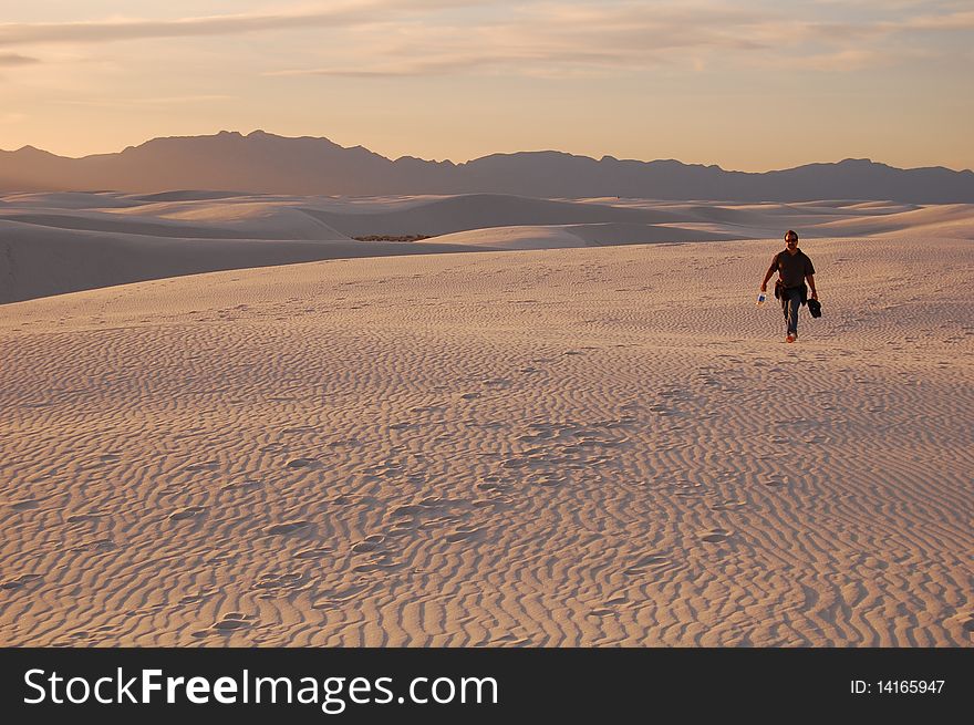 Hiker in White Sands National Park, NM at sunset with mountains and tracks on dunes. Hiker in White Sands National Park, NM at sunset with mountains and tracks on dunes