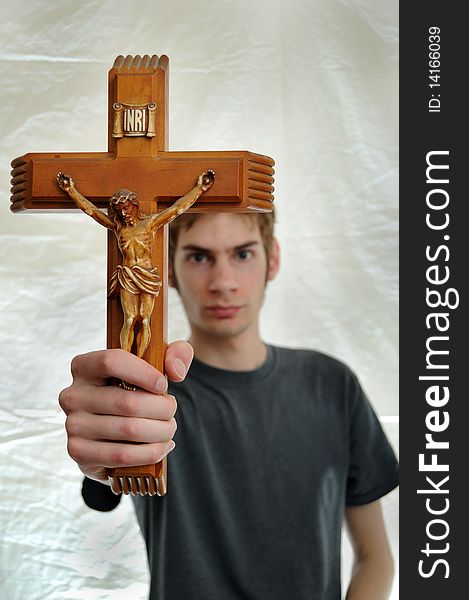 Young man holds up a wooden crucifix of Jesus. Young man holds up a wooden crucifix of Jesus.