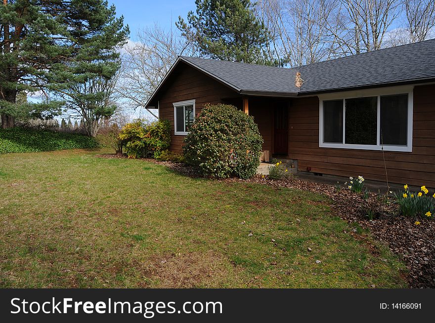 Country brown rural home showing its front grass lawn. Country brown rural home showing its front grass lawn