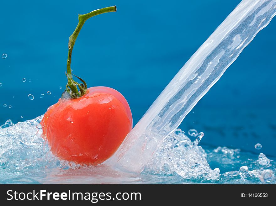 Red tomato with green stalk and splash water over white background