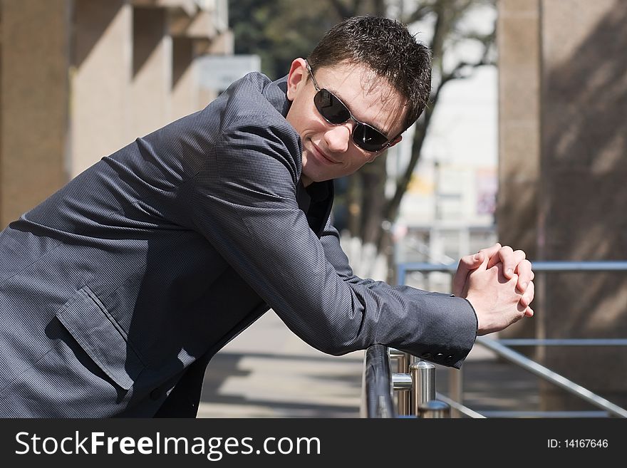 Young Adult Businessman Leans On Handrails