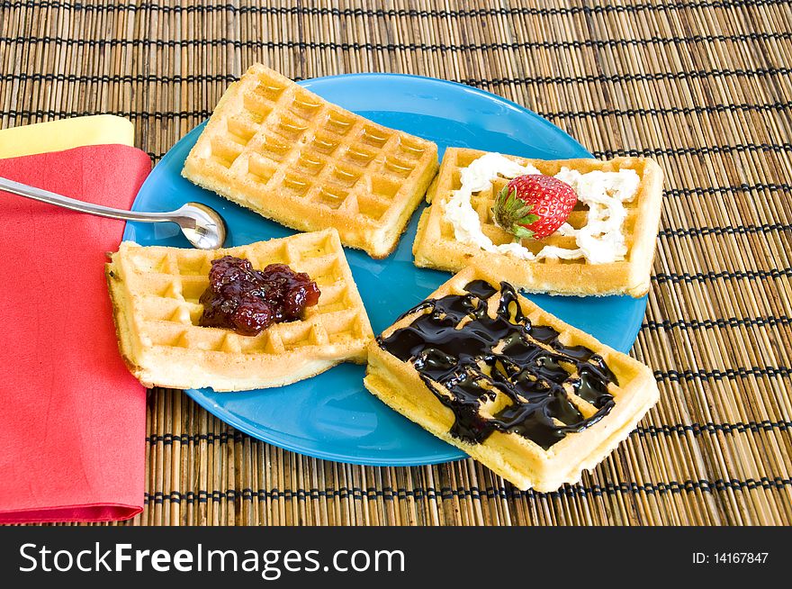 Freshly made waffles with chocolate, jam, honey and strawberries