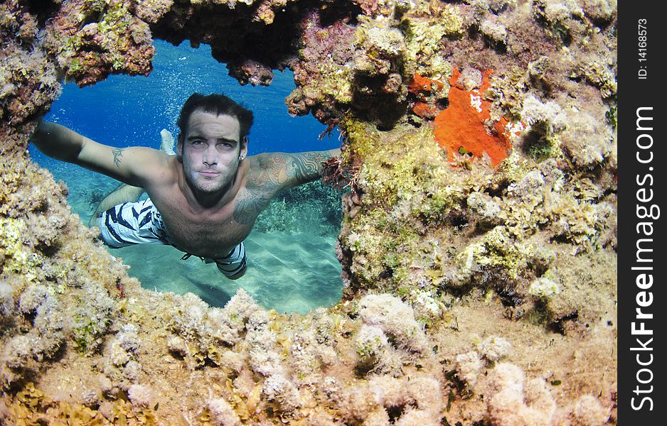 Freediver swimming through coral hole. Freediver swimming through coral hole