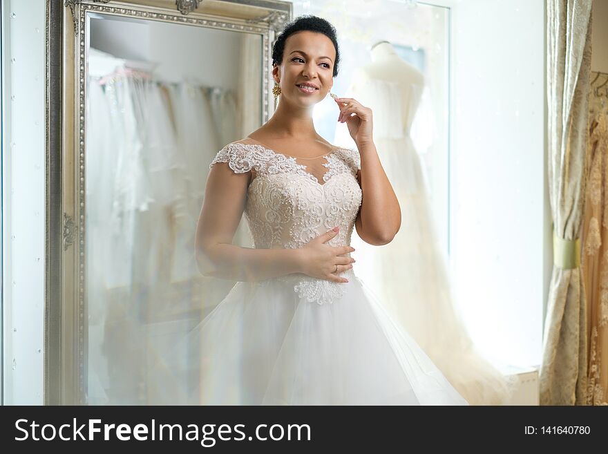 Beautifu bride choosing wedding dress in a wedding salon.