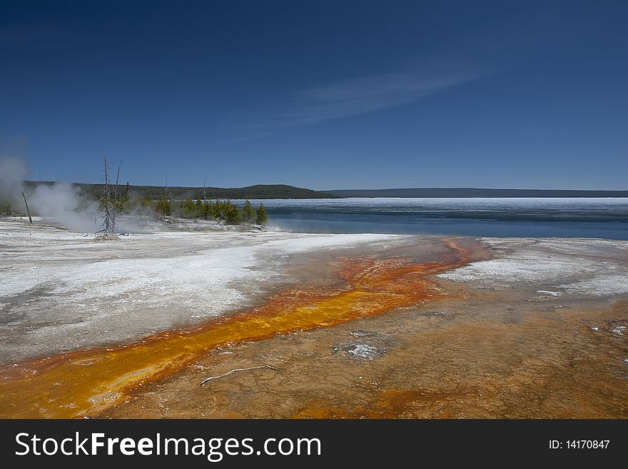 Shore of the lake Yellowstone in the beginning of spring, smoke from the hot water, geyser