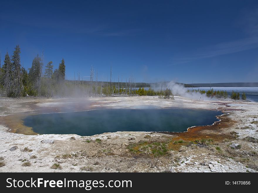 Shore of the lake Yellowstone in the beginning of spring, smoke from the volcanic ground water, geyser