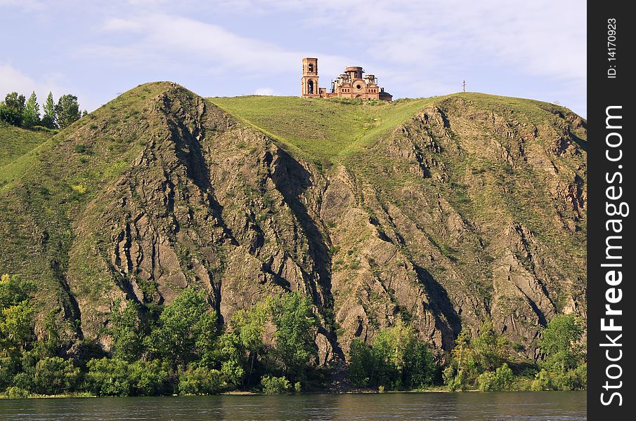 Under construction temple on high to river bank Yenisei