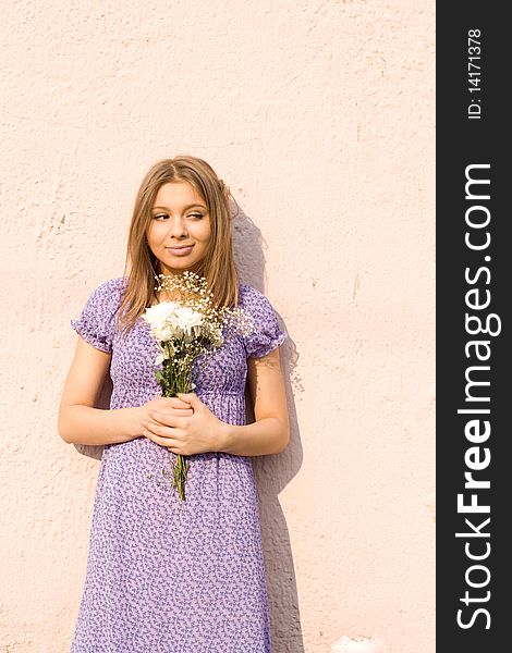 Girl with flowers standing outdoor near wall